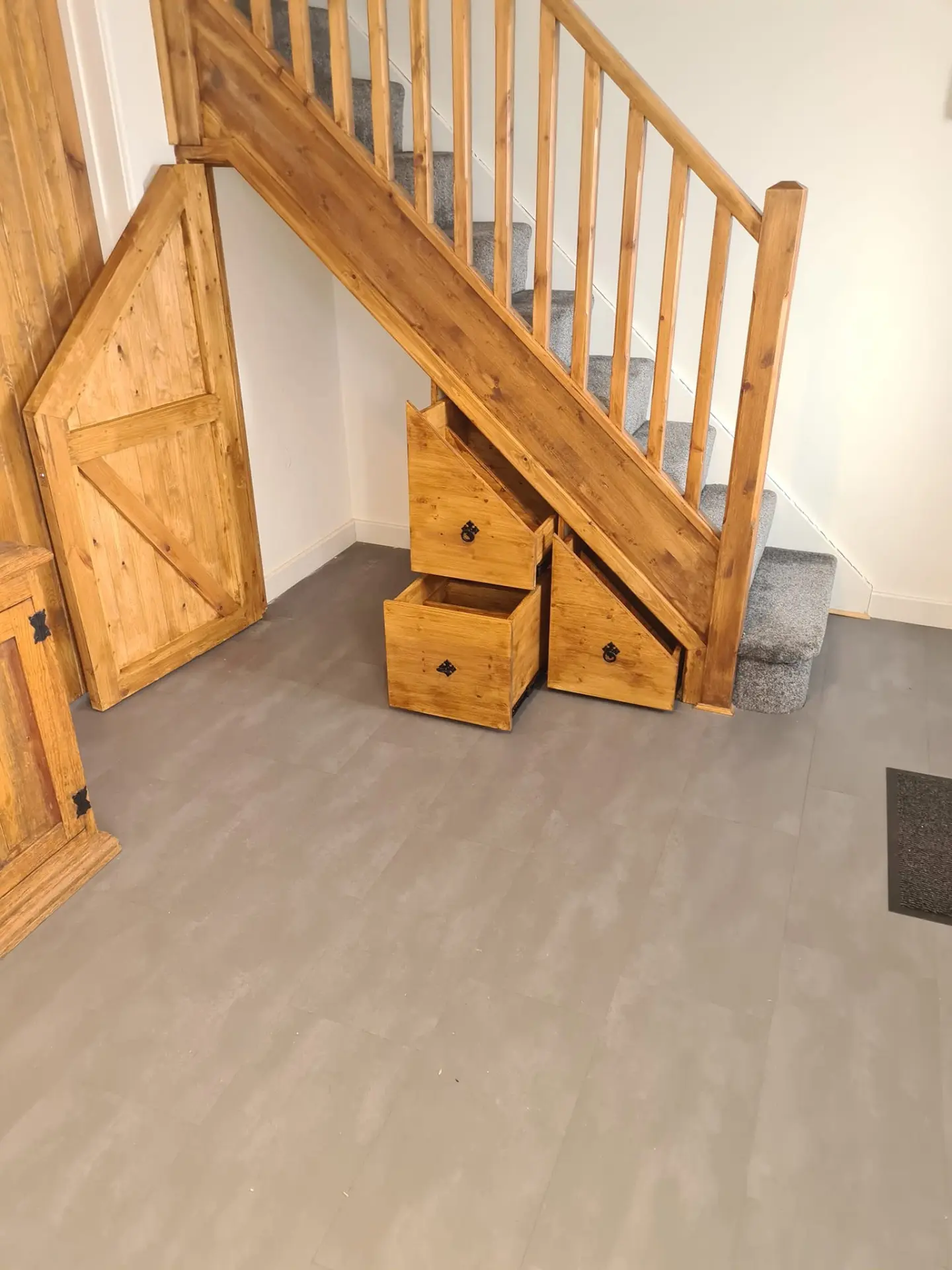 Timber understairs storage with pull-out drawers and a plank door