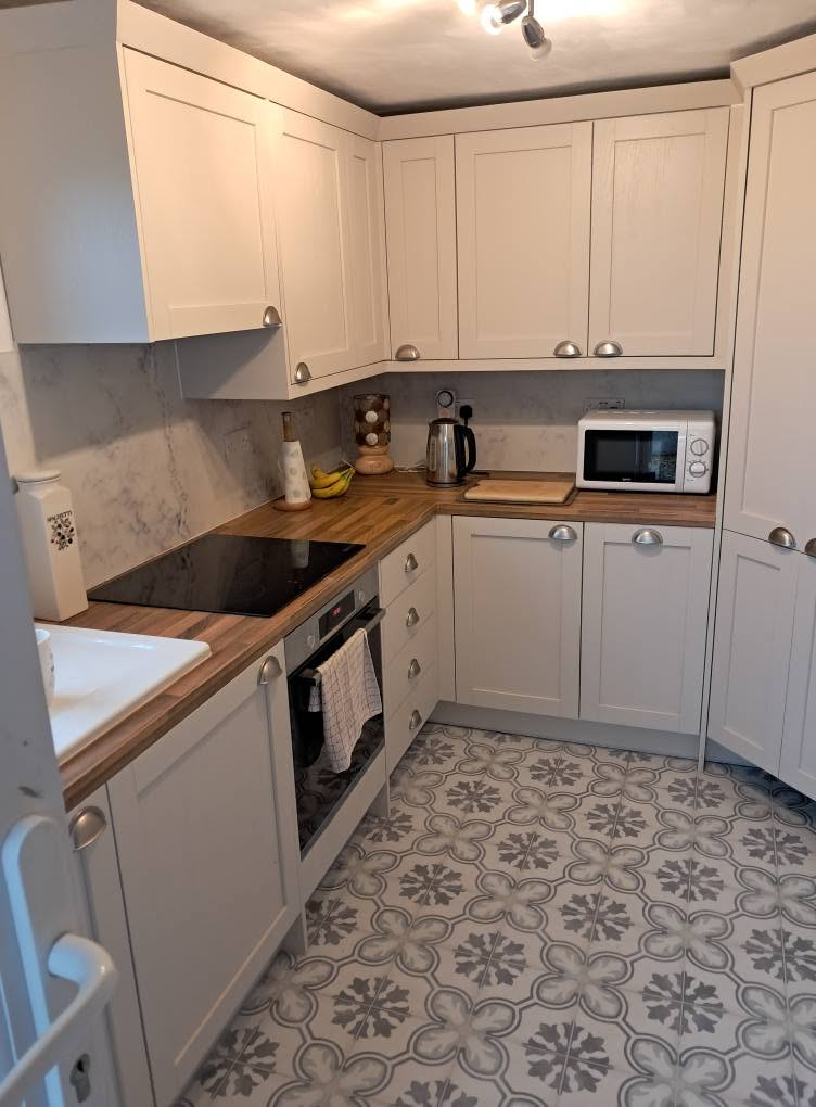Fitted kitchen with oak worktops and patterned tiled floor